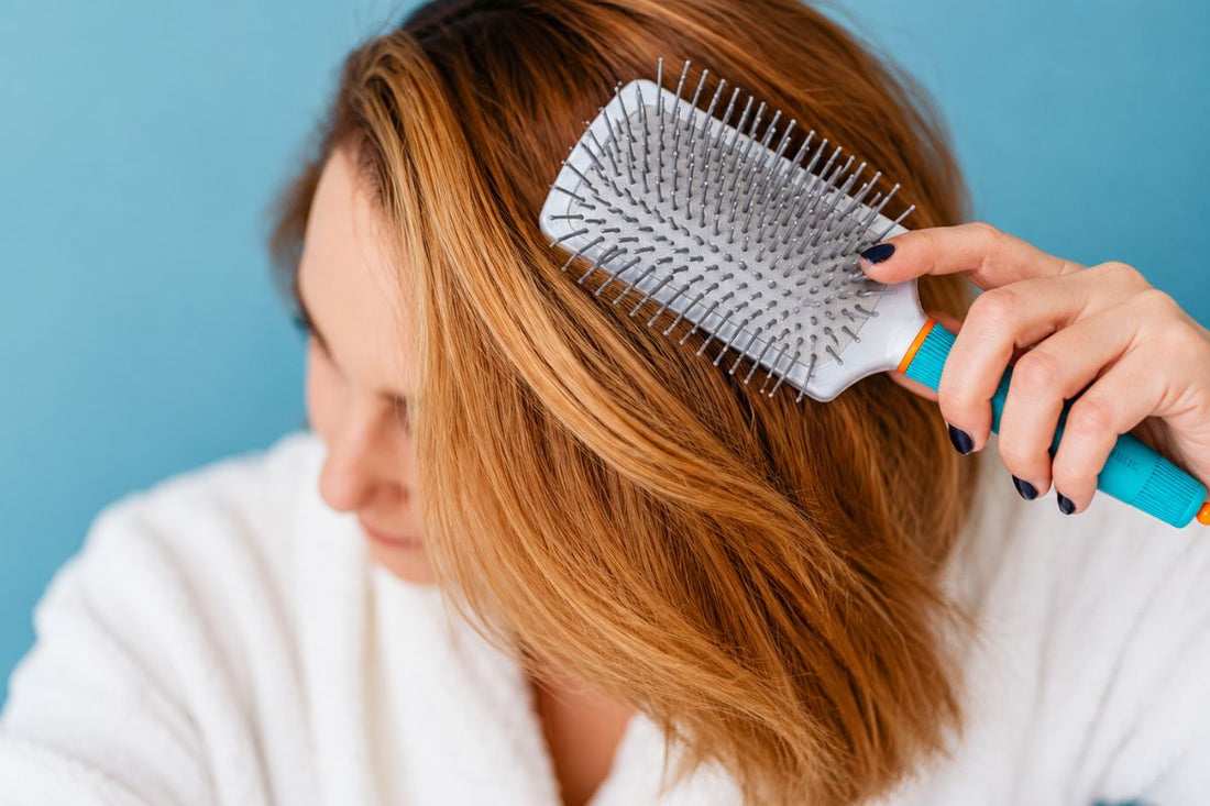Red head holding a Maroccanoil paddle brush.